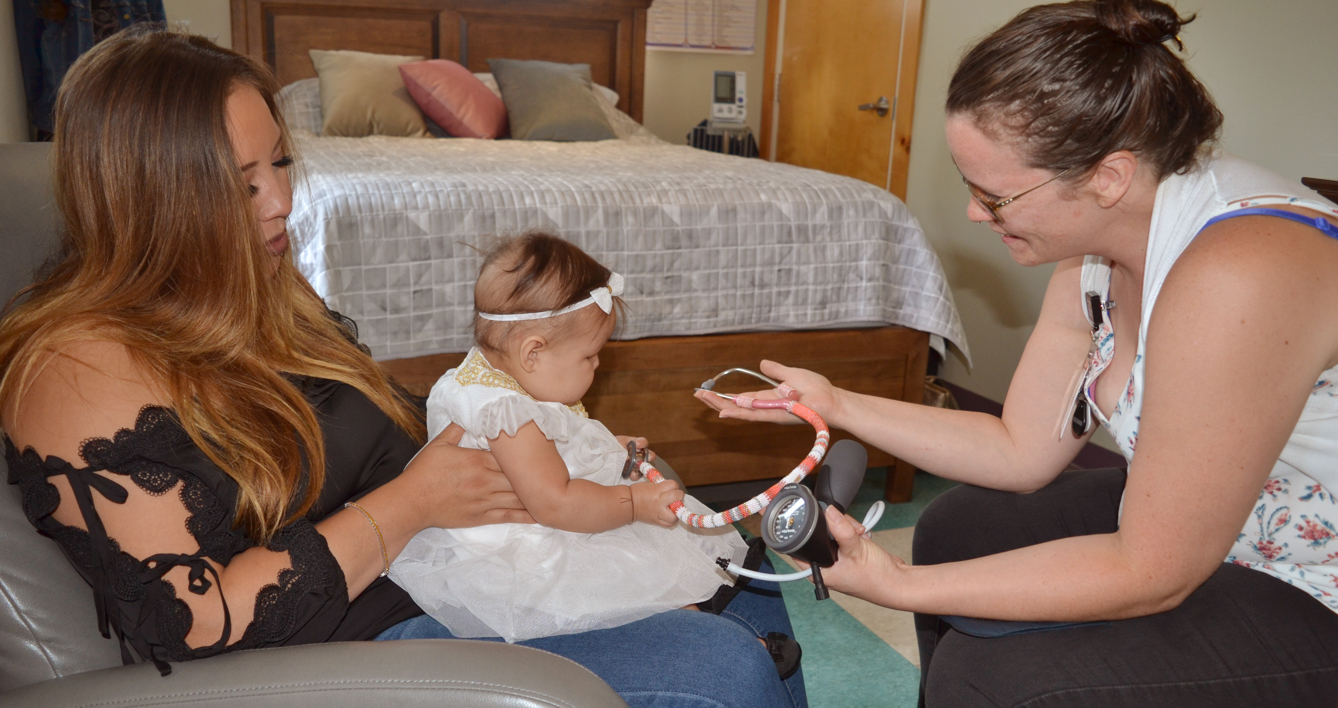 Mother holds baby as an Indigenous midwife holds a stethoscope