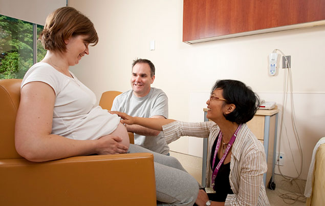 Photo of a couple with their midwife in hospital.