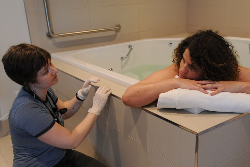 Picture of a labouring person in birth pool looking at their midwife.